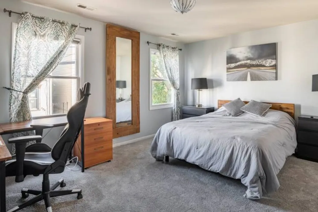 Carpeted bedroom with a bed, desk and office chair