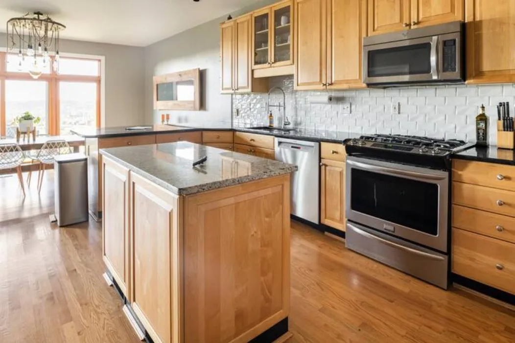 Kitchen with wooden cabinets, granite island and stainless steel appliances
