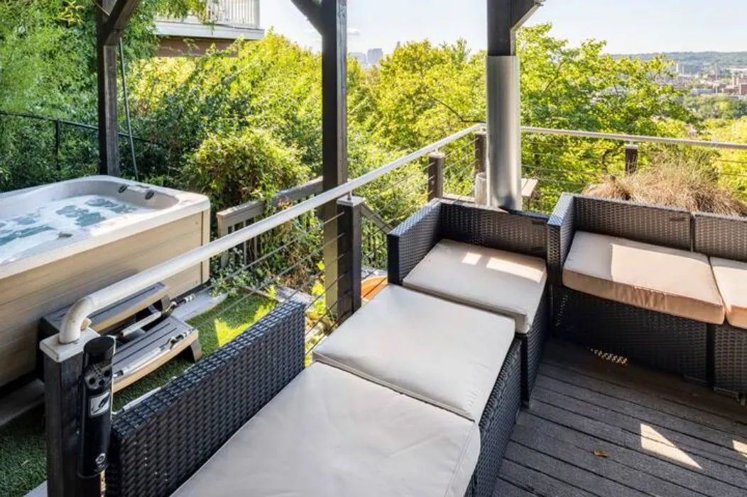 Hot tub on the deck beside cushioned seating with trees behind
